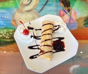 olden brown fried cheesecake chimichanga with drizzles of strawberry, honey, and chocolate, served with whipped cream and a maraschino cherry.